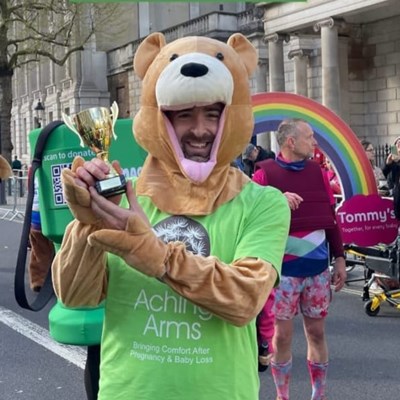 Adam dressed as our Dandelion Bear winning the Mascot Dash, holding his throphy for Aching Arms at The London Landmarks Half Marathon 2024