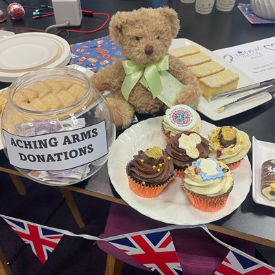 a tea party showing some cakes and an Aching Arms Comfort Bear