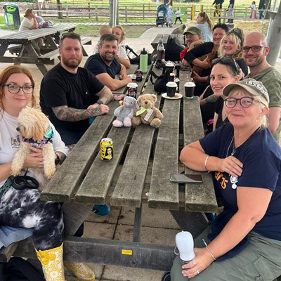 Photo of people who attended the Aching Arms Walk Together event, sitting at a table outside enjoying refreshments in Itchen Valley Country Park, Southampton